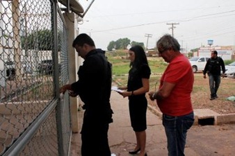 De camisa vermelha, Lucídio Colinetti chega à delegacia escoltado por uma promotora e delegado da Polícia Civil